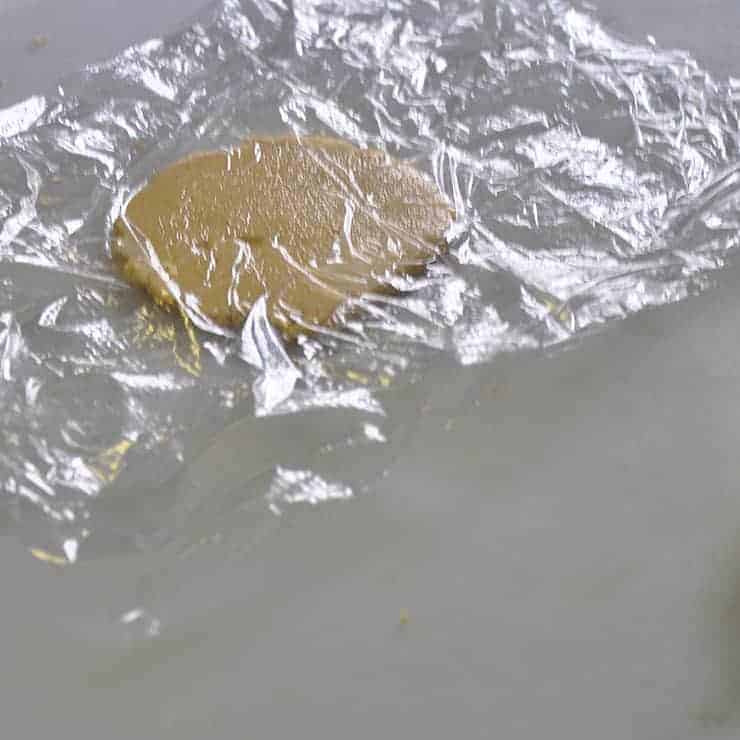 A flattened tortilla between two sheets of plastic wrap.