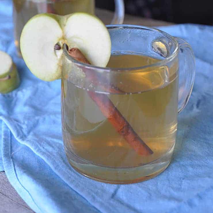 Apple Ginger Hot Toddy in irish coffee mug with cinnamon stick and apple slice.