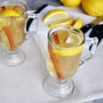 best hot toddy recipe. Hot toddy on a table with lemon, cinnamon, and a cutting board.