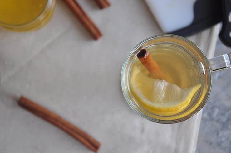 picture of hot toddy from the top of the drink on top of table cloth and with some cinnamon sticks.