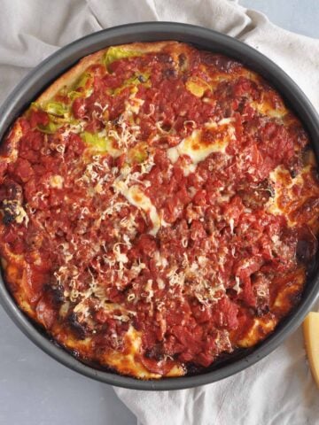 Chicago Deep dish on a table with parmesan cheese in the lower corner and it all on a napkin