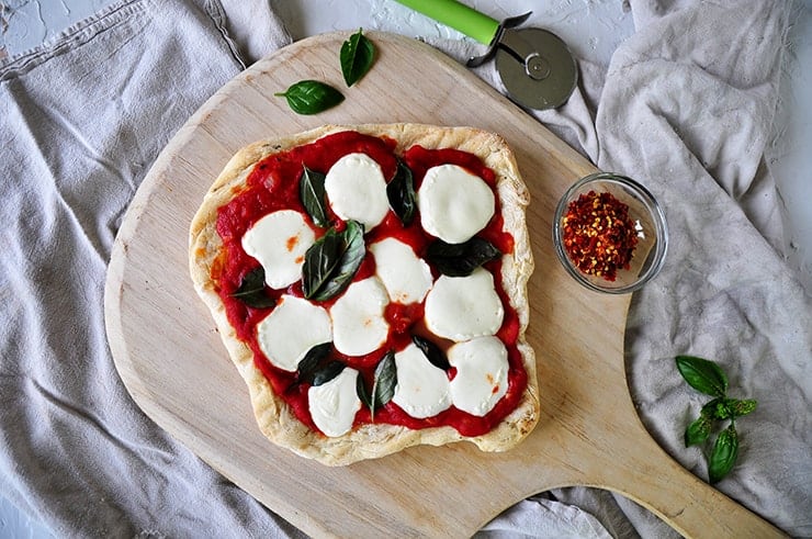 A Grilled Plain Pizza with Basil on it