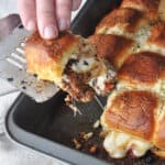 Baked pizza sliders being pulled from the oven pan