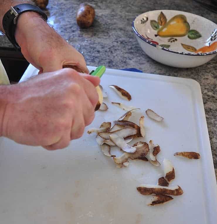 Peeling potatoes on a cutting board.