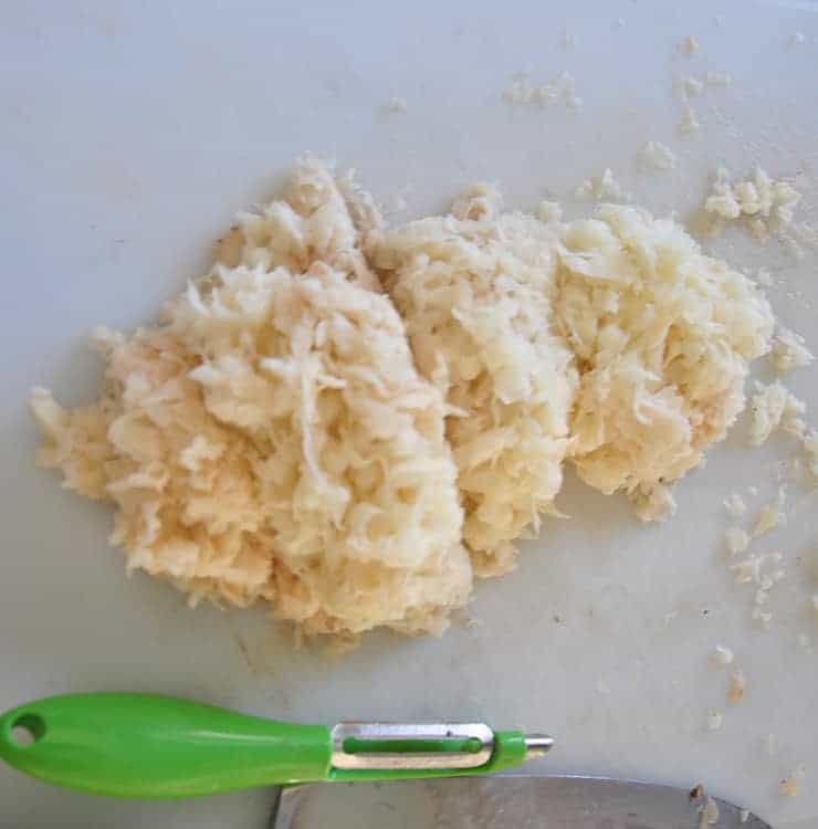 Shredded potatoes on a cutting board.