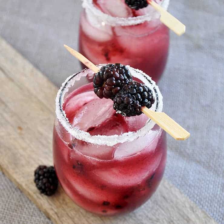 A blackberry black dog cocktail on a wood plank