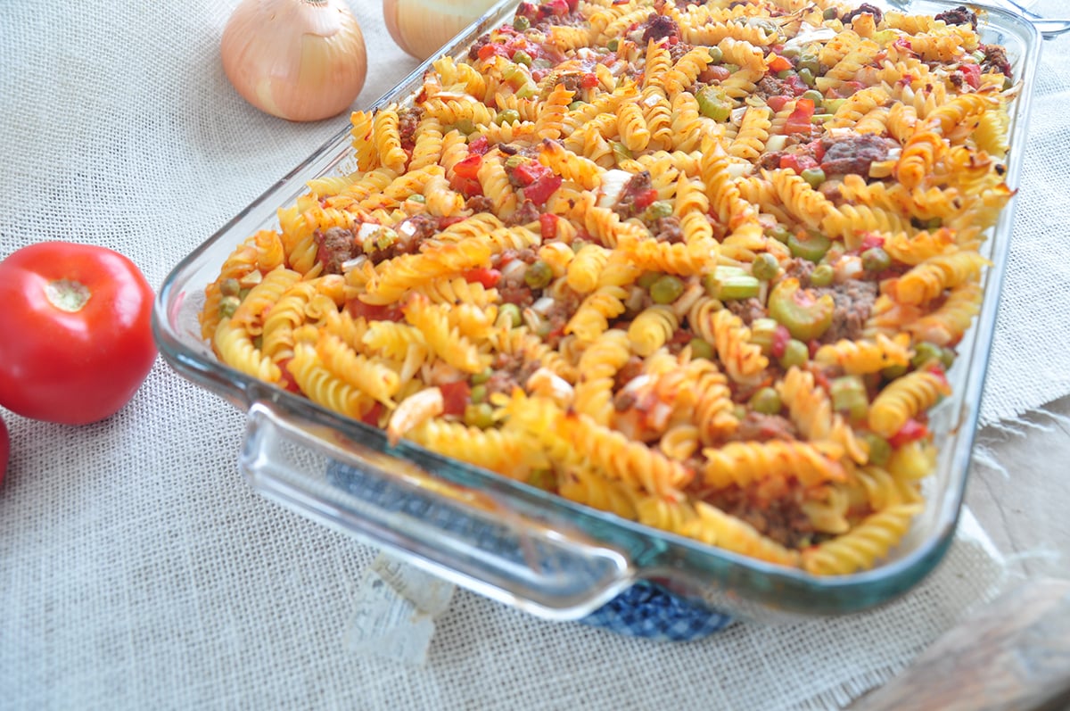 a picture of the completed hot dish recipe. A tomato and onions in the background.