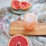 greyhound cocktail recipe on wood platform with grapefruits