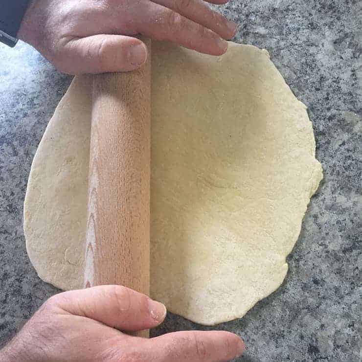 Rolling out bread dough in order to make noodles with.