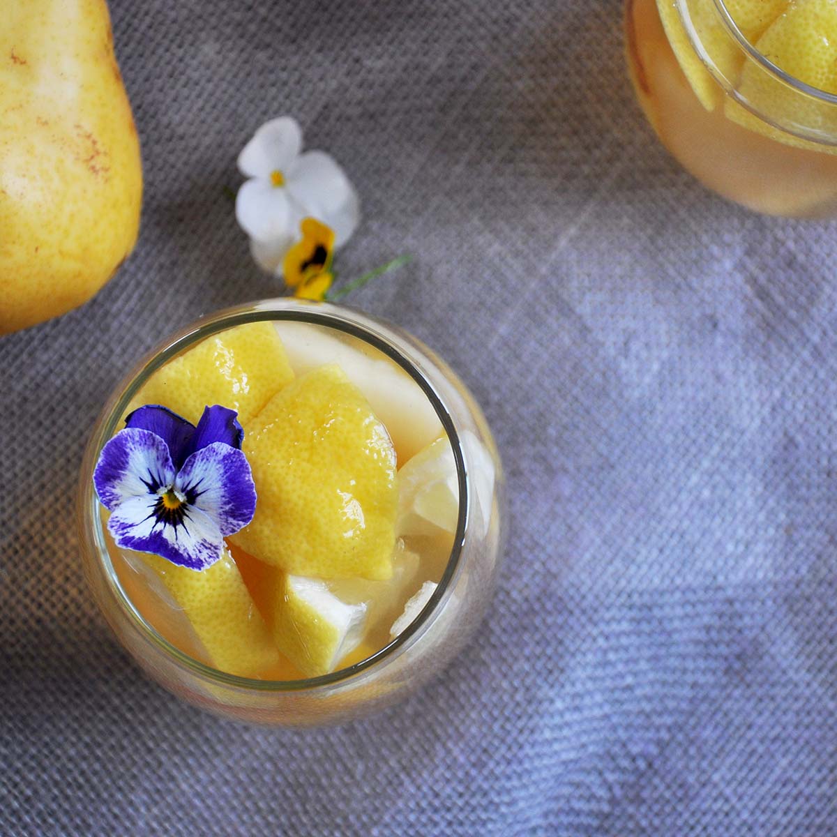 overhead shot of the best white sangria recipe. There is a purple and white viola garnishing this sangria.