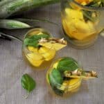 Two glasses of our pineapple basil moscato sangria with a pitcher and a pineapple head in the background.