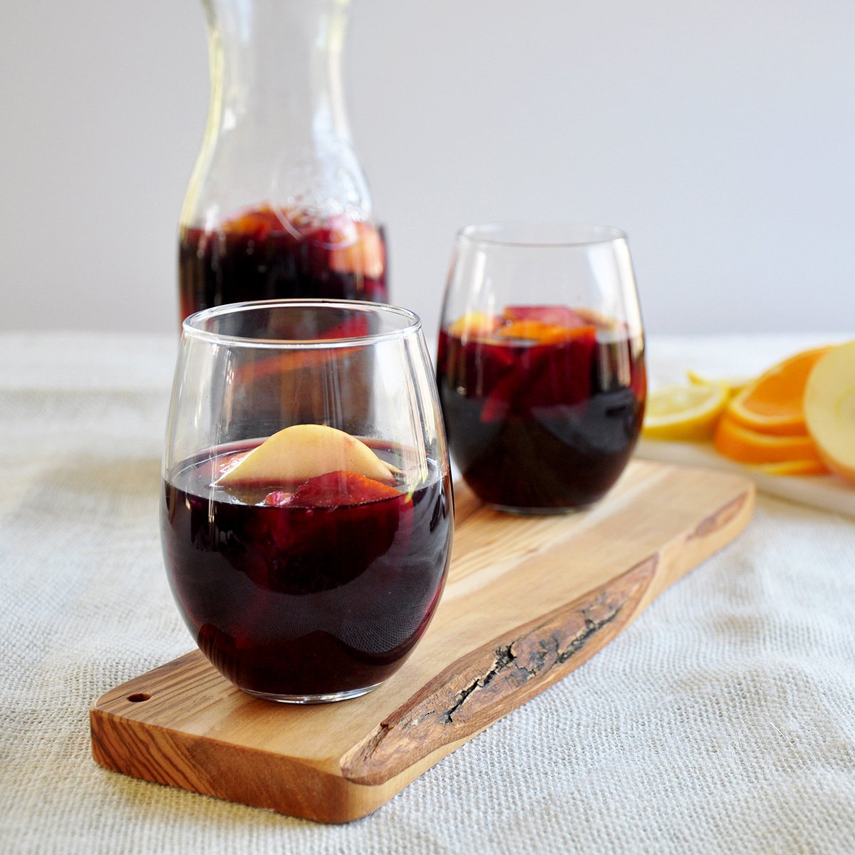 Side view of two sangrias with a carafe of the same in the background