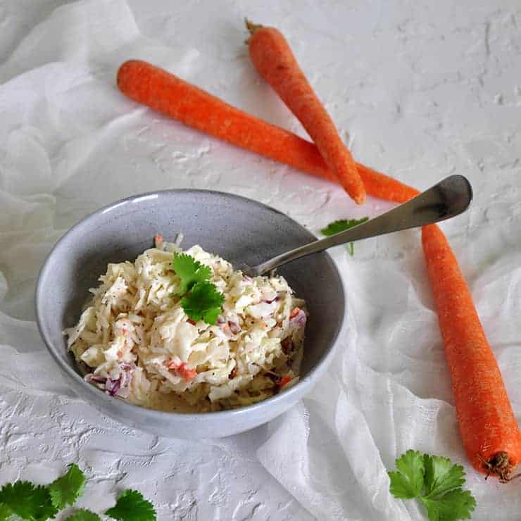 side view of this easy coleslaw recipe with greenery on top and carrots