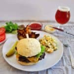 A plate featuring a sirloin burger, a surley Furious, macaroni salad, and some jojos