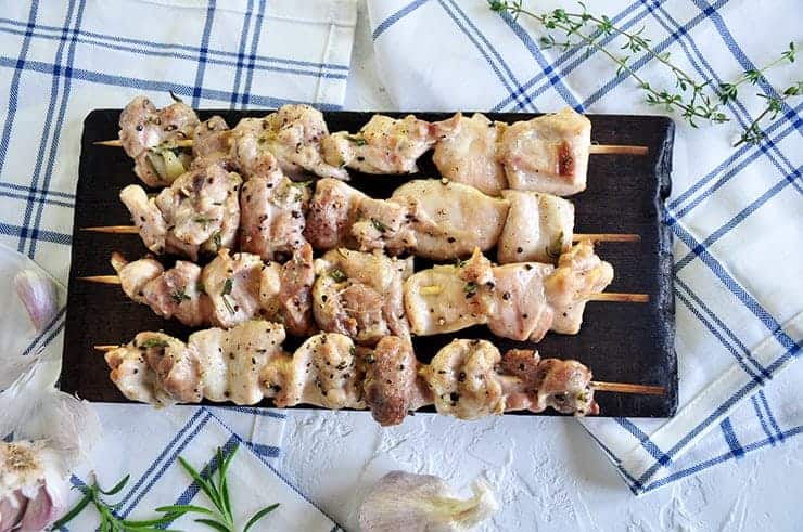 Four Chicken Shish Kabobs on a wood plank.