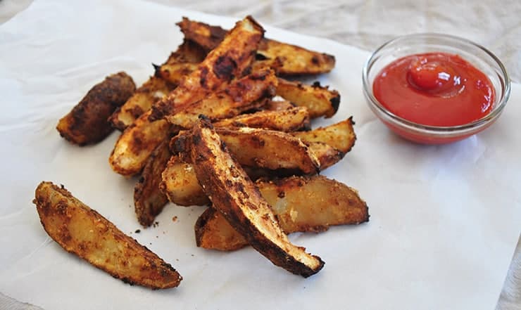 finished servings of potatoes on some paper and served with a small glass bowl of ketchup