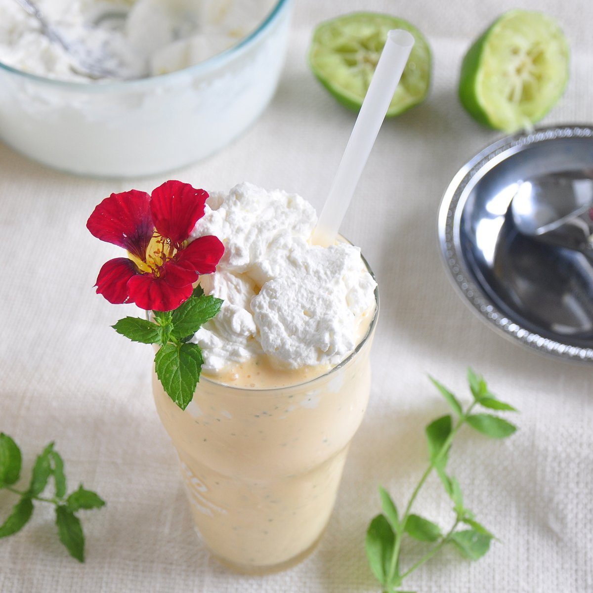 The Mojitarita Milkshake - a mint margarita dessert on a white cloth with mint laying around the drink. 