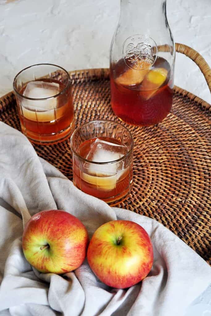 Carafe of apple brandy on a platter. Two Braeburn apples showing