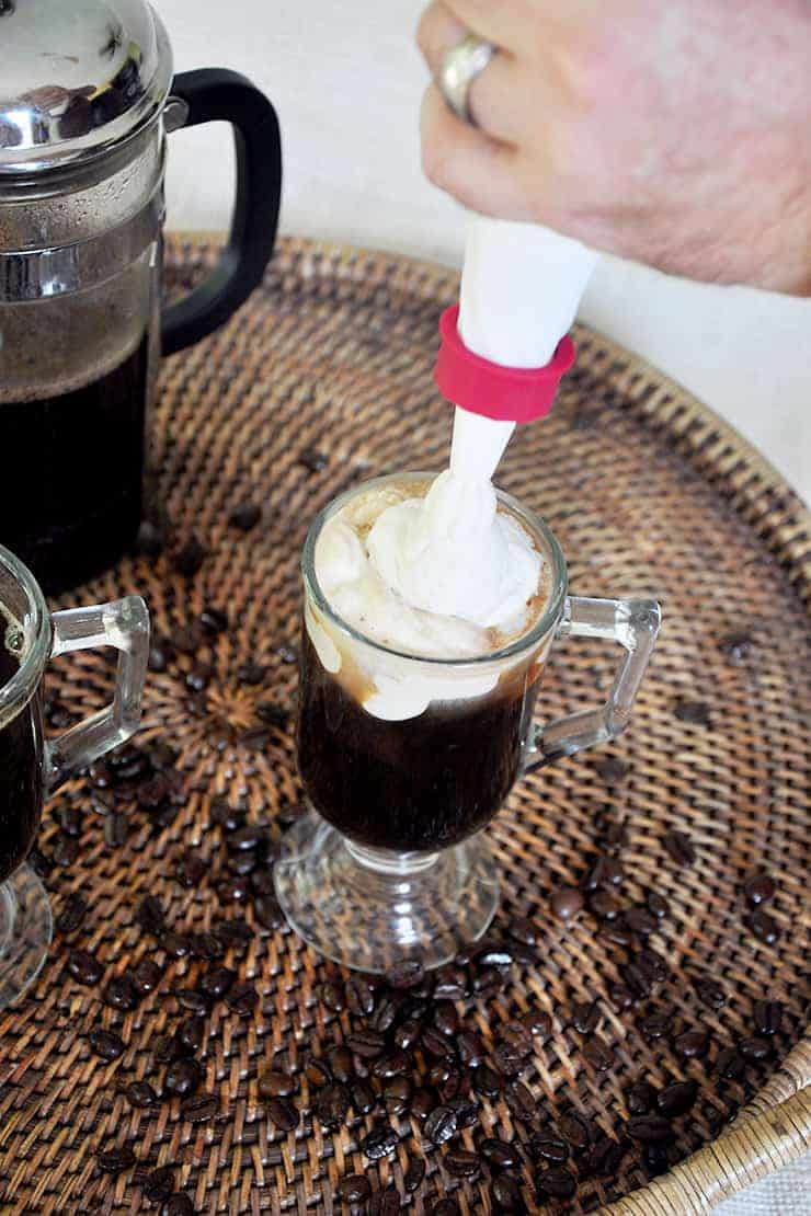 Placing Kahlua whipped cream on top of Russian coffee.