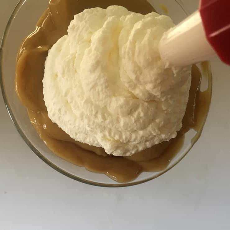 Adding Whipped Cream to the dessert.