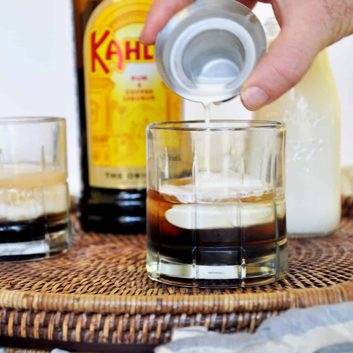 Pouring some cream on top of an almost complete cocktail.