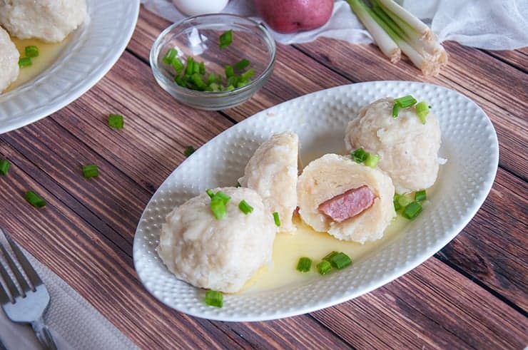 A Klubb Norwegian dumpling cut in half and exposing the ham that is in the middle.