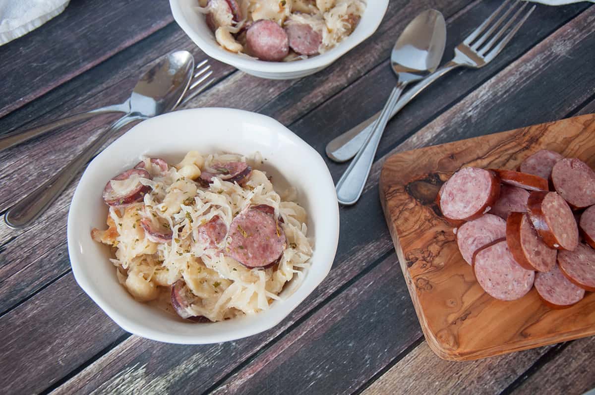 Sauerkraut and sausage in a white bowl.