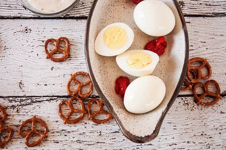 Overhead shot of pickled eggs. We have peppers, ranch, and pretzels in the background