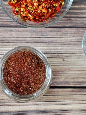 Taco Seasoning in a small mason jar with paprika and crushed peppers off to the side.