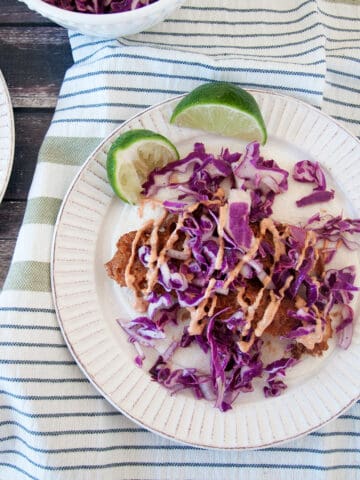 Overhead shot of the fried beer battered fish tacos with the red cabbage coleslaw and sriracha baja sauce on top.