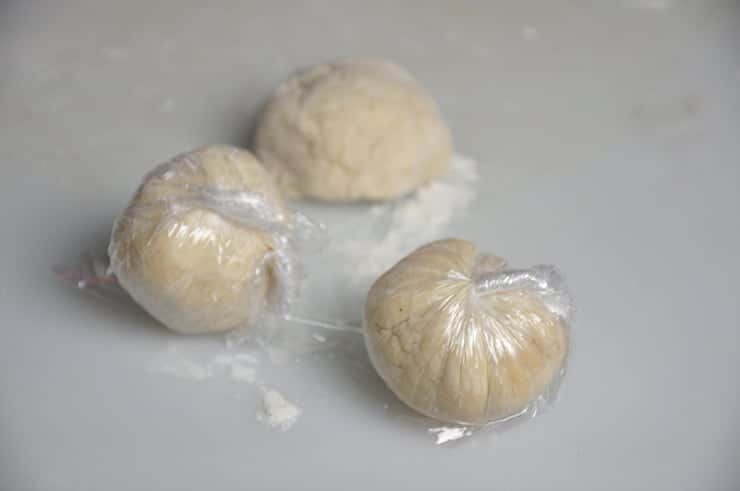 Three balls of dough individually wrapped in plastic wrap