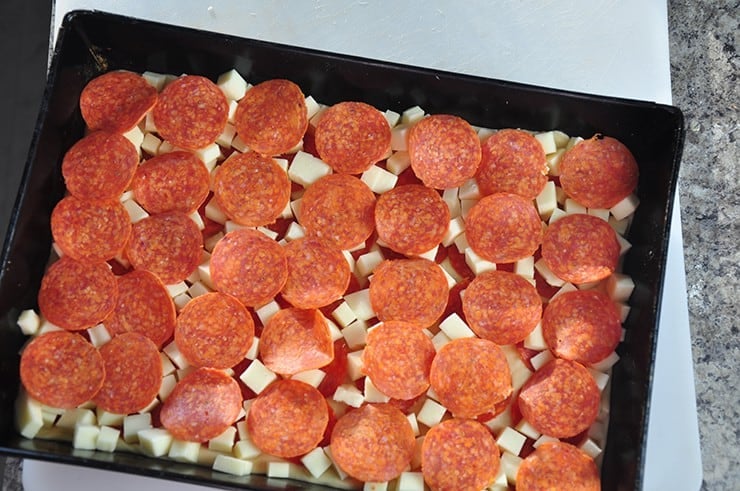 Pizza in pan with cheese and pepperoni, but no sauce.