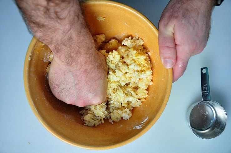 Using hand to smoosh the thawed tater tots, egg, and flour together.