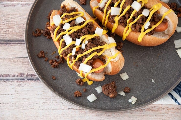 Completed Detroit Coney Dog overhead shot on dark plate and topped with onion and oney