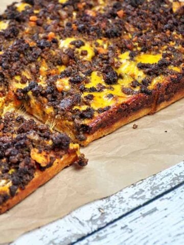 Detroit Style Coney Island pizza on a brown paper mat.