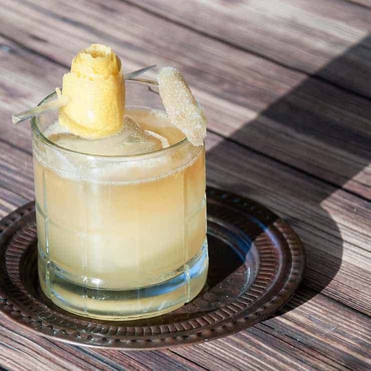 Shot of a Penicillin cocktail with lemon and ginger garnish.