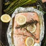 Overhead view of a tin foil grilled salmon fillet recipe, still in foil and some asparagus on the side.