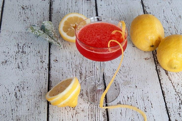 Paper Plane Cocktail on a picnic table with three lemons.