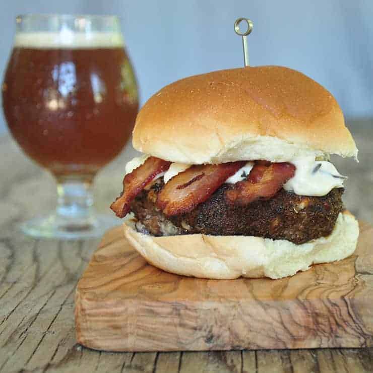 Black and Blue Burger on a cutting board with a pint of beer in the background.