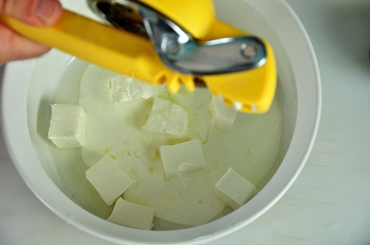 Squeezing lemon into a white bowl that had Crema Mexicana and cream cheese