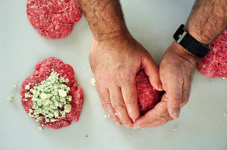 Enclosing two quarter pound patties around a bit of blue cheese for this hamburger.