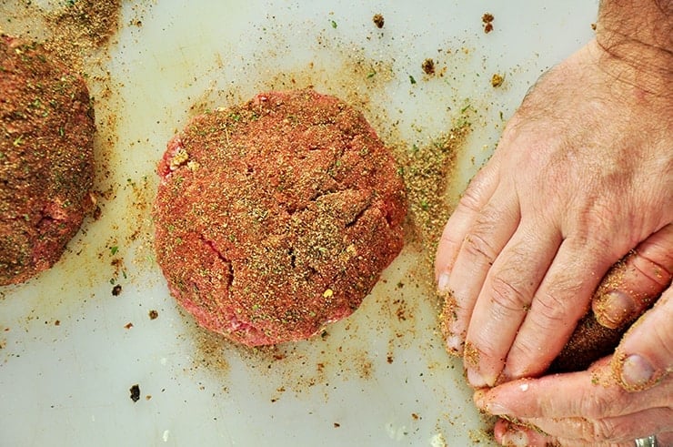 Adding Black rub onto hamburger patties.