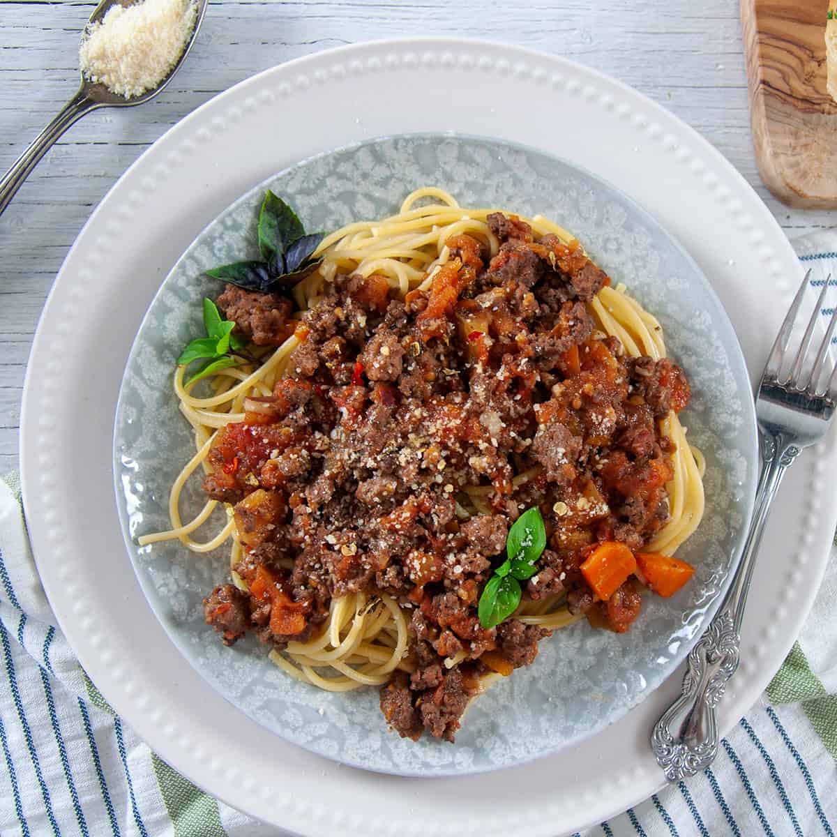 Traditional Pasta Sauce Recipe served over Spaghetti noodles on a white plate with garlic bread and cheese on the side