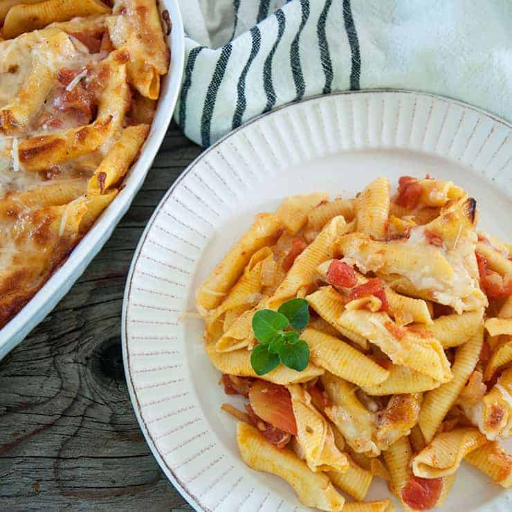 Pasta Al Forno serving on a white plate with a casserole dish off to the side.