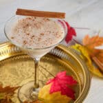 RumChataTini cider cocktail on a gold platter with Fall leaves garnishing the scene.