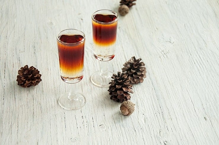 Two Total Yodel Shots on a table with pine cones in the background.