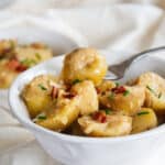 Kartoffelsalat in a white bowl with a fork in one piece of the potato salad