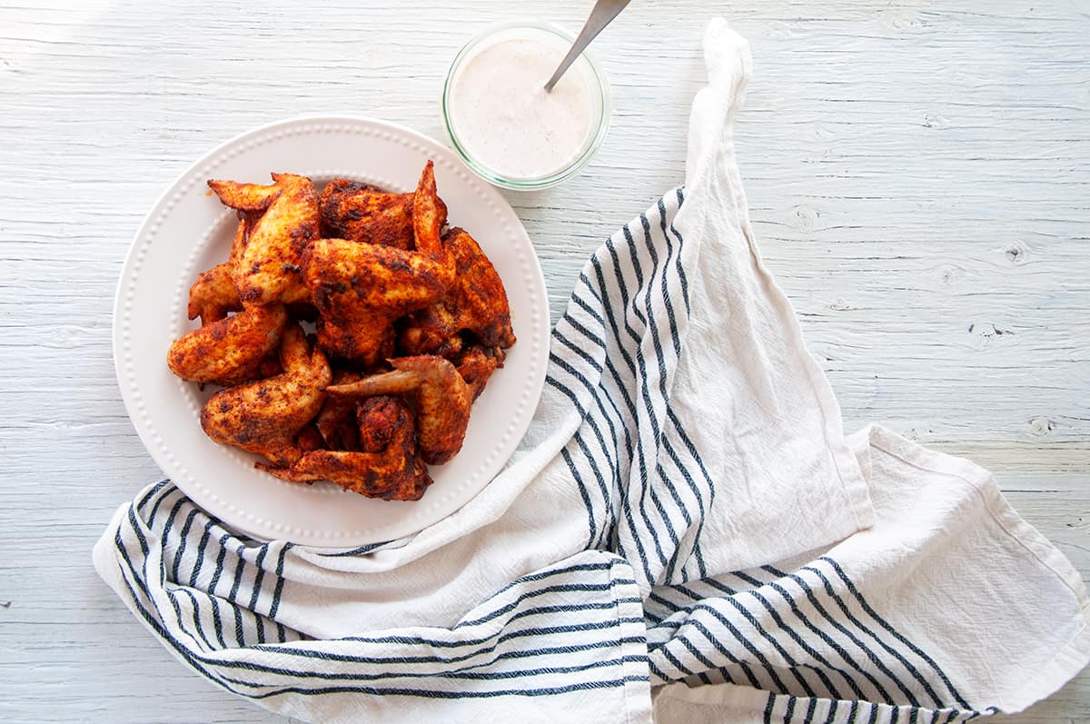 Plate of dry rub chicken wings and some dipping sauce.