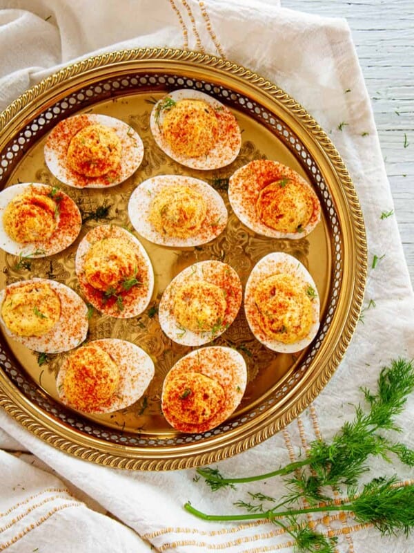 A Plate of Dill Pickle Spicy Deviled Eggs on a gold platter and dill on the side.