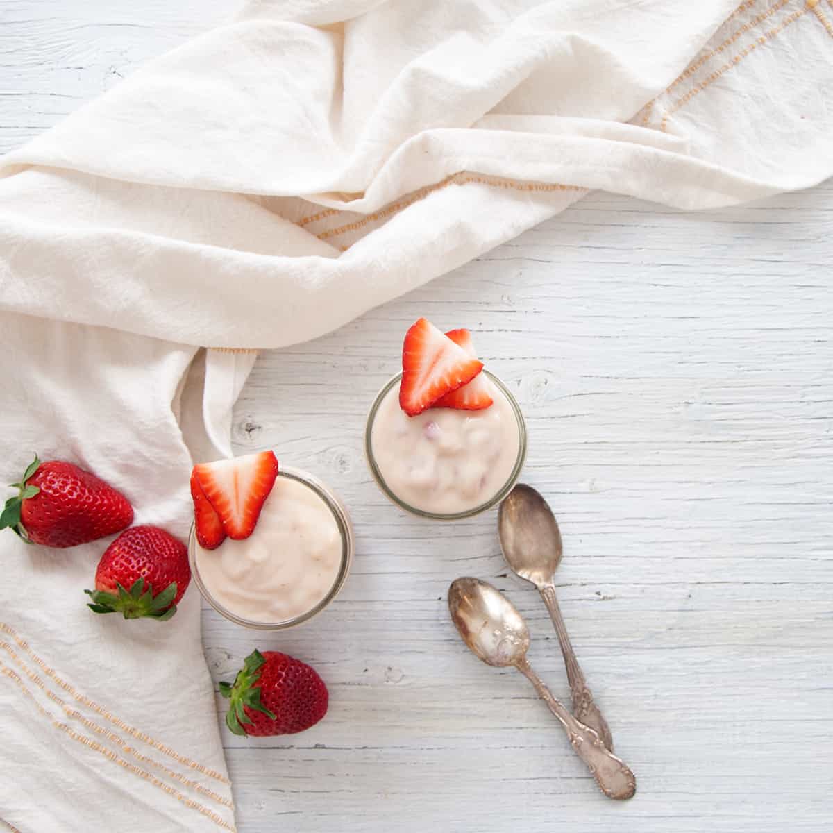 Fresh Strawberry Pudding overhead picture in two mason jars with some strawberries and spoons on the side.